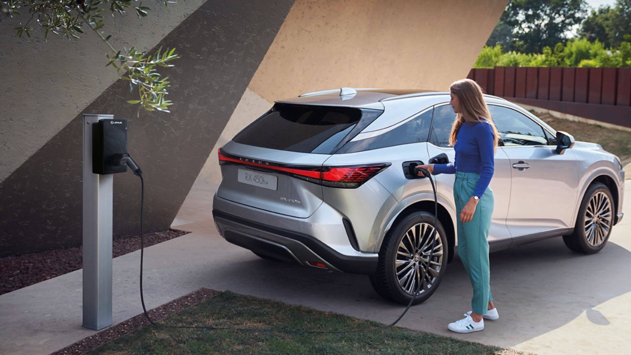 A person plugging a charger into a Lexus RX 450h+